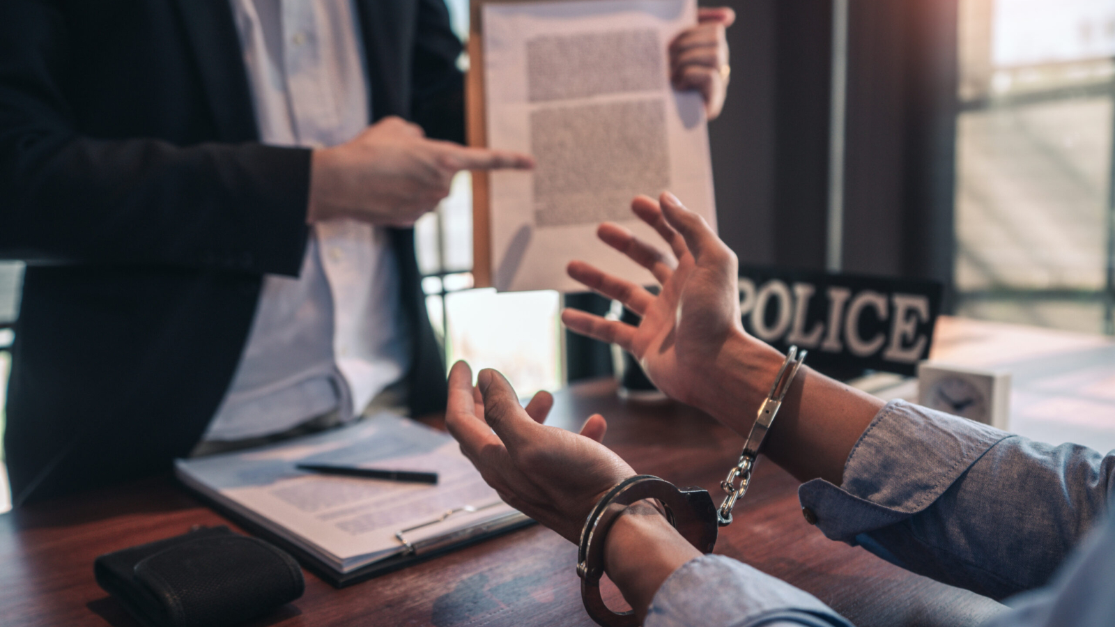 Police officer interrogating suspect or criminal man with handcuffs arrested at the investigation